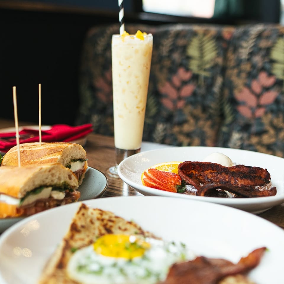 Restaurant table with a sandwich, two breakfast plates, and tall beverages.