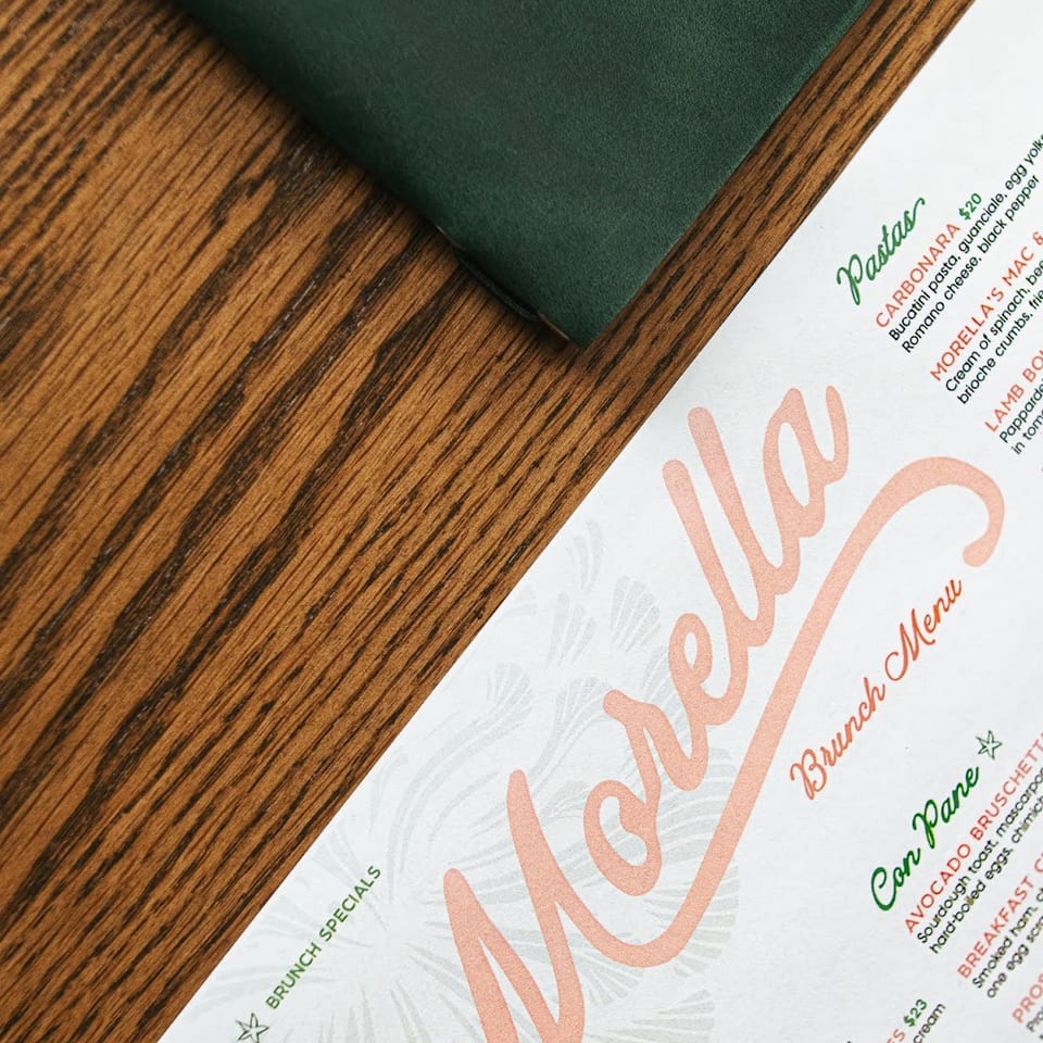 Morella Brunch Menu with a green napkin on a wooden table.