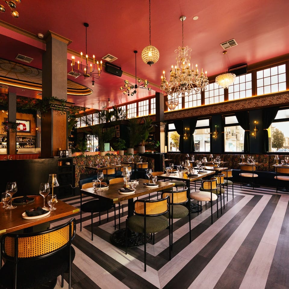 Elegant dining room featuring a red ceiling, ornate chandeliers, and a striking striped floor.